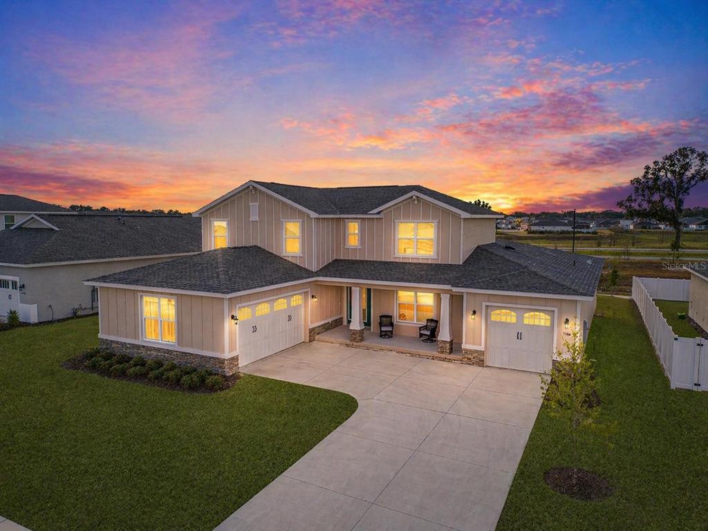 A two-story suburban house with beige siding, a stone base, and a three-car garage — 7610 SW 60TH STREET, OCALA, FL