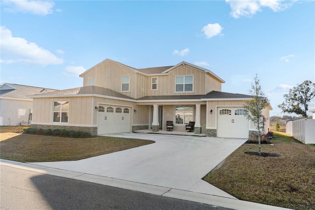 A two-story house with beige vertical siding, a stone base, and a three-car garage — 7610 SW 60TH STREET, OCALA, FL