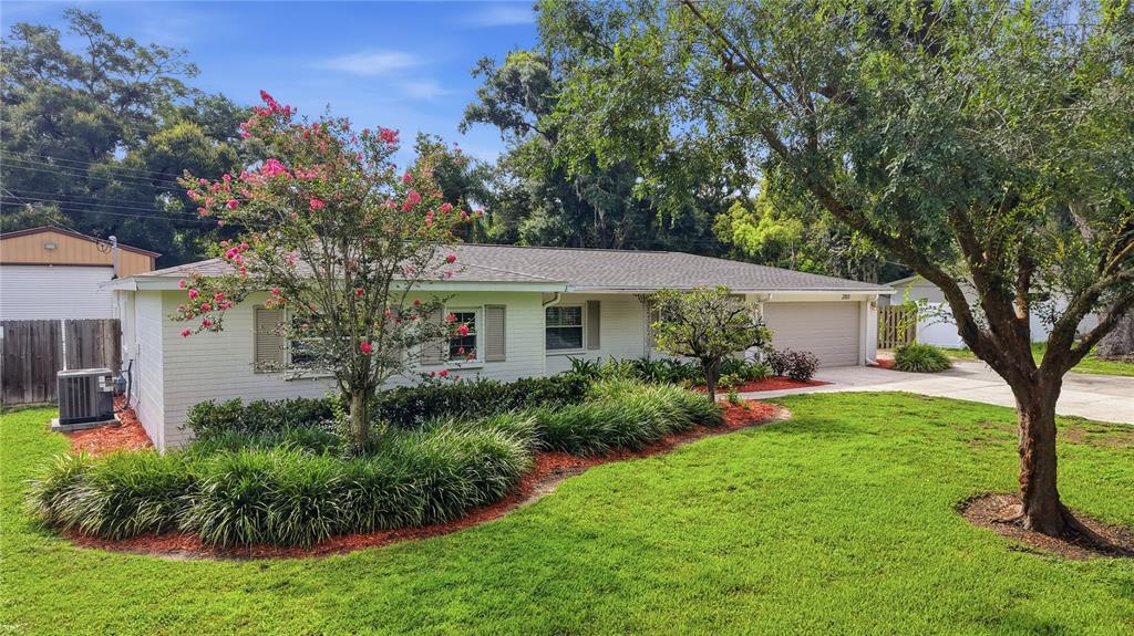 A white, single-story ranch-style house with a front lawn, landscaping, and a two-car garage — 2103 RAMBLEWOOD LANE, BRANDON, FL