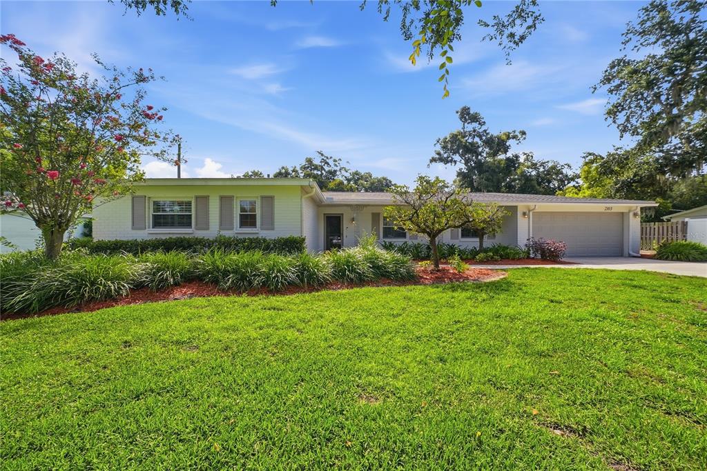 A single-story white brick house with a two-car garage and a landscaped front yard — 2103 RAMBLEWOOD LANE, BRANDON, FL