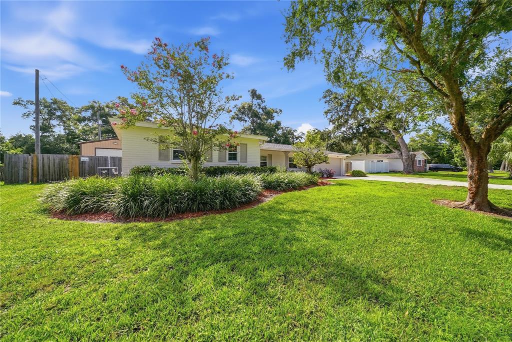 A single-story house with a lawn, landscaping, and a driveway under a blue sky — 2103 RAMBLEWOOD LANE, BRANDON, FL