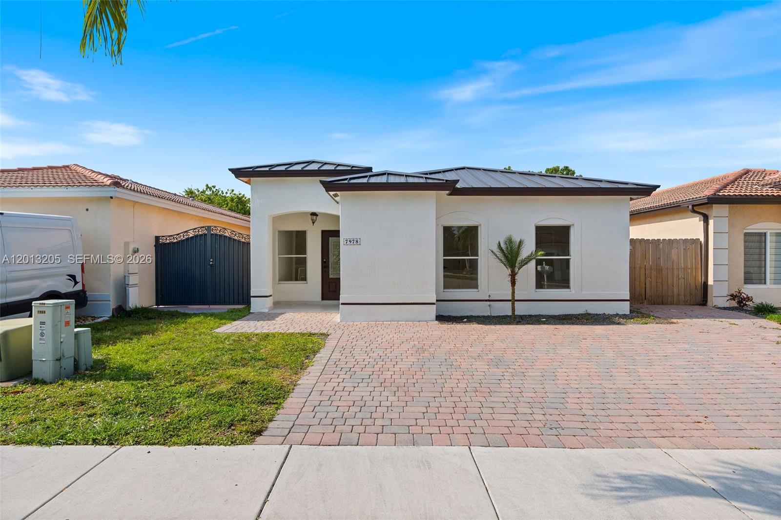 A single-story white house with a metal roof and a brick paver driveway — 7978 NW 200th St, Hialeah FL 33015, HIALEAH, FL