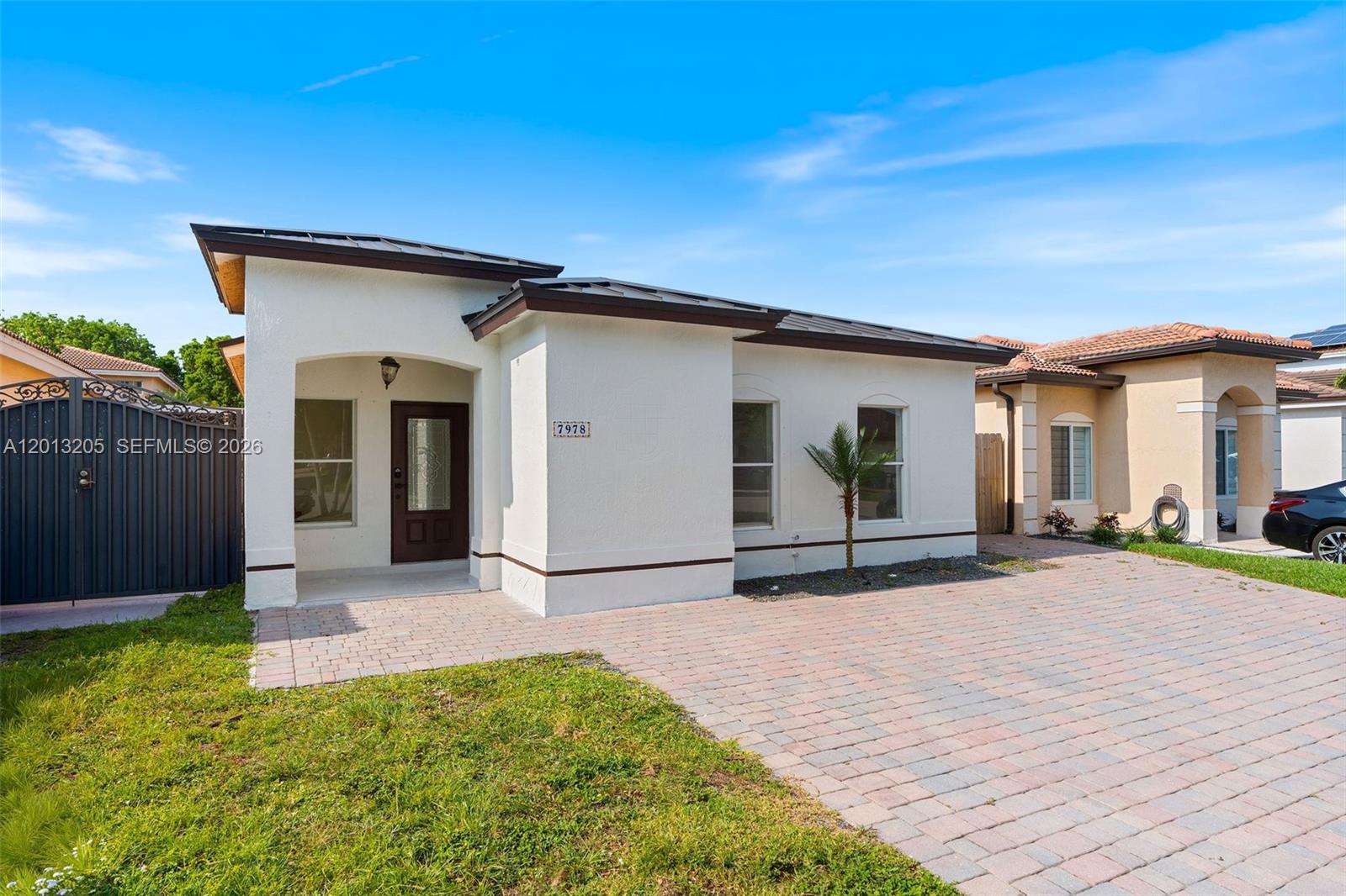 A white single-story house features a paved driveway, a dark front door, and a metal roof — 7978 NW 200th St, Hialeah FL 33015, HIALEAH, FL