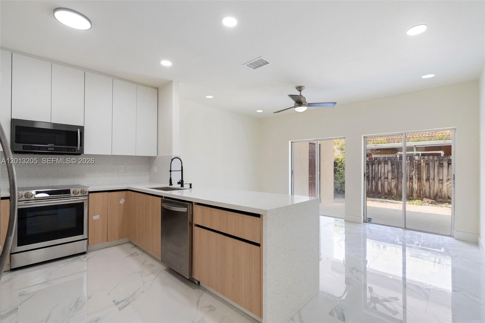 A modern kitchen features light wood cabinets, white countertops, stainless steel appliances, and tile flooring — 7978 NW 200th St, Hialeah FL 33015, HIALEAH, FL