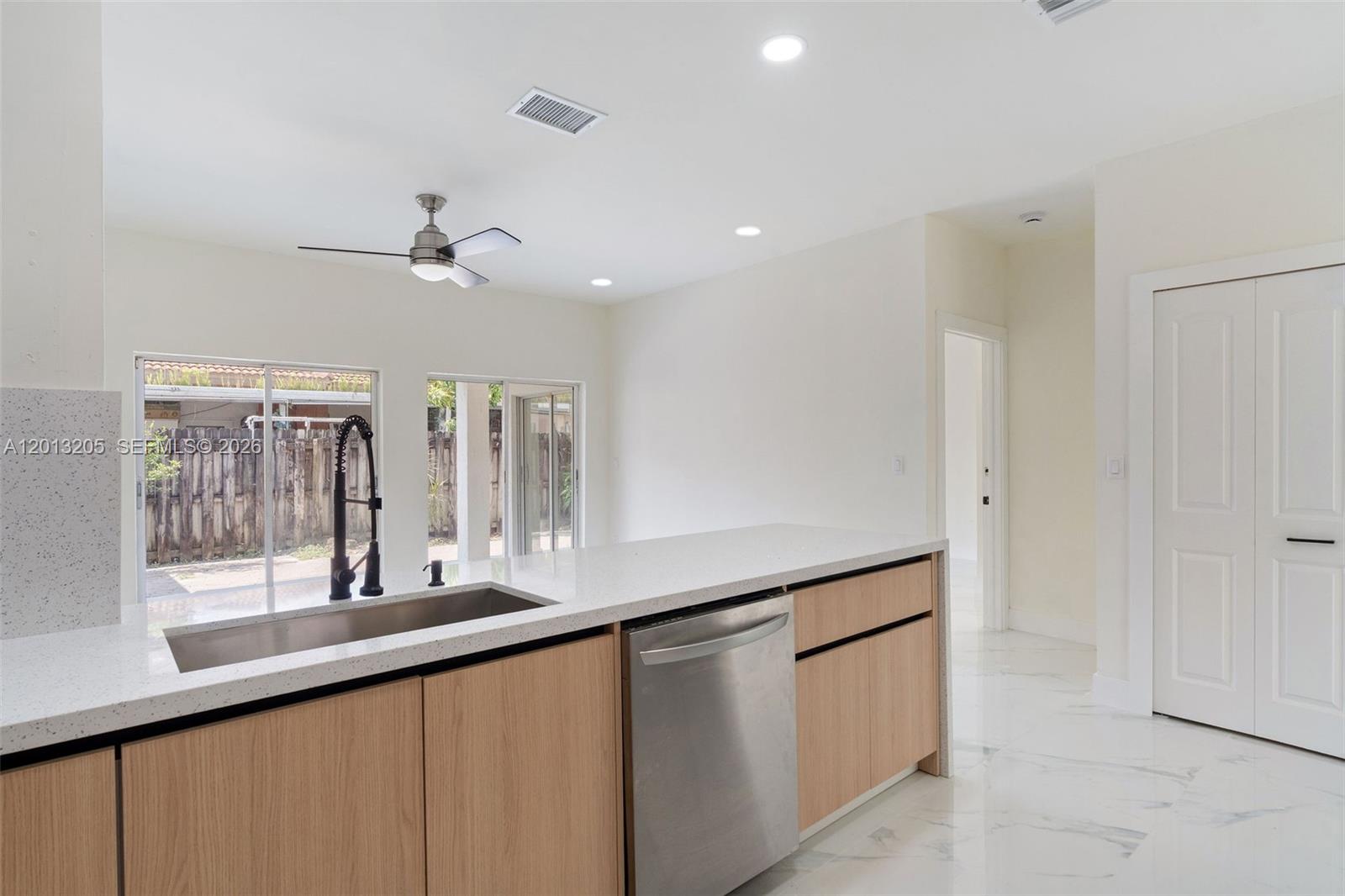 A modern kitchen features light wood cabinets, white quartz countertops, and stainless steel appliances — 7978 NW 200th St, Hialeah FL 33015, HIALEAH, FL