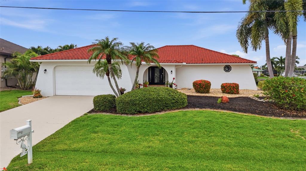A single-story house with a red tile roof, white stucco walls, and a two-car garage — 3433 NIGHTHAWK COURT, PUNTA GORDA, FL
