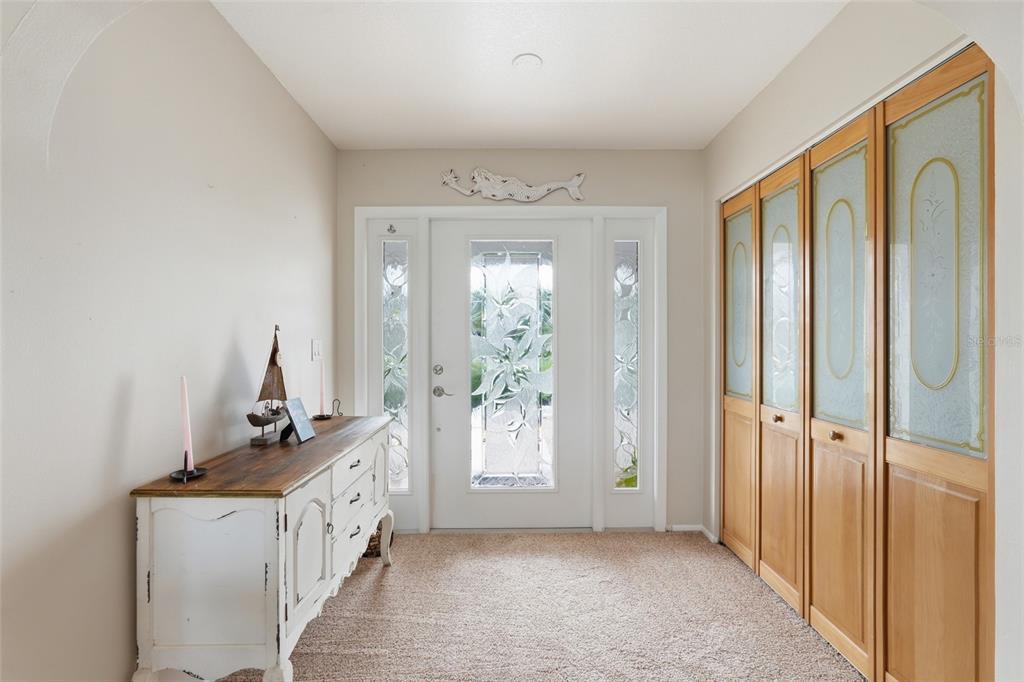 An entryway features a white front door with glass panels, a wooden console table, and closets — 3433 NIGHTHAWK COURT, PUNTA GORDA, FL