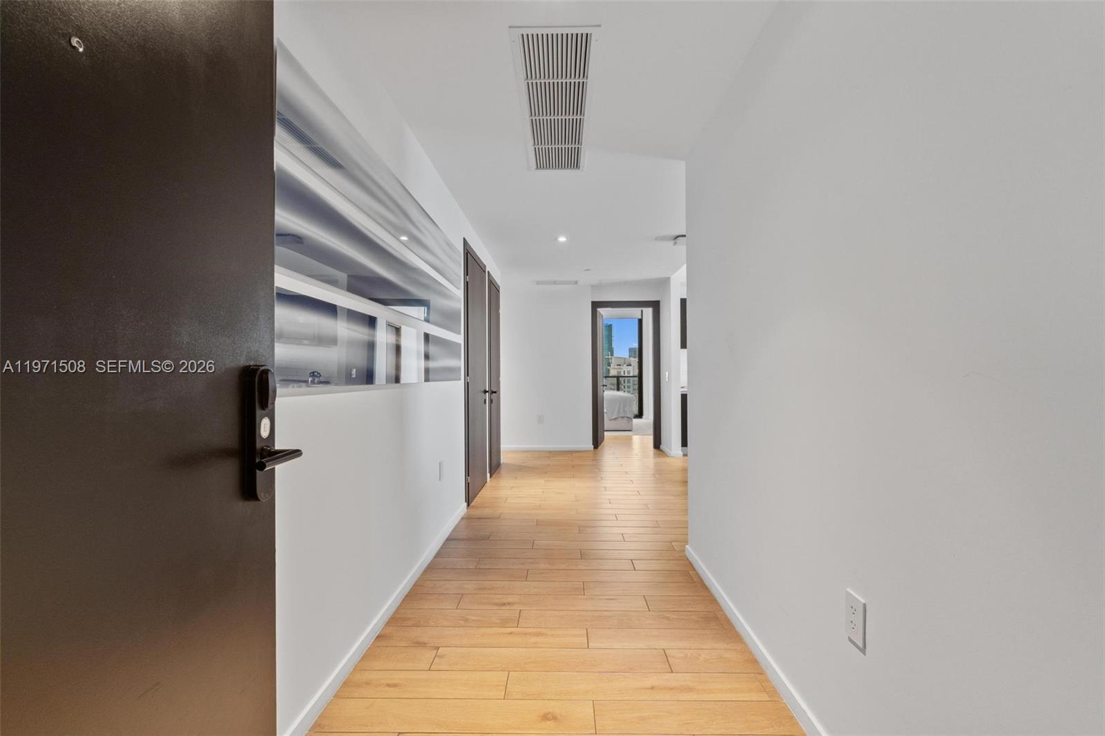 A hallway with light wood-look flooring leads to a doorway showing a city view — 398 NE 5th St # 3218, Miami FL 33132, MIAMI, FL