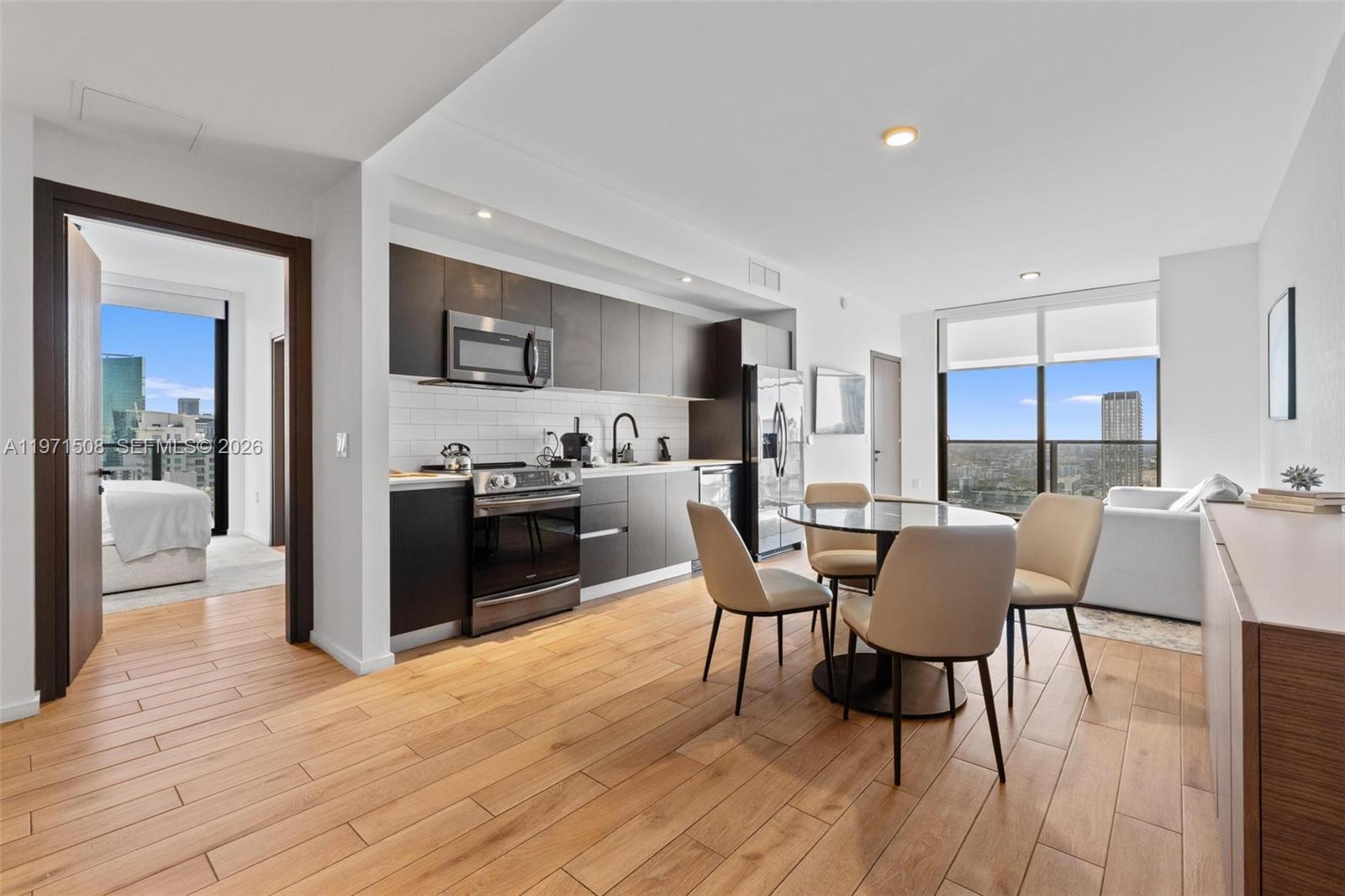 A modern kitchen and dining area feature dark cabinetry, light wood floors, and floor-to-ceiling windows — 398 NE 5th St # 3218, Miami FL 33132, MIAMI, FL