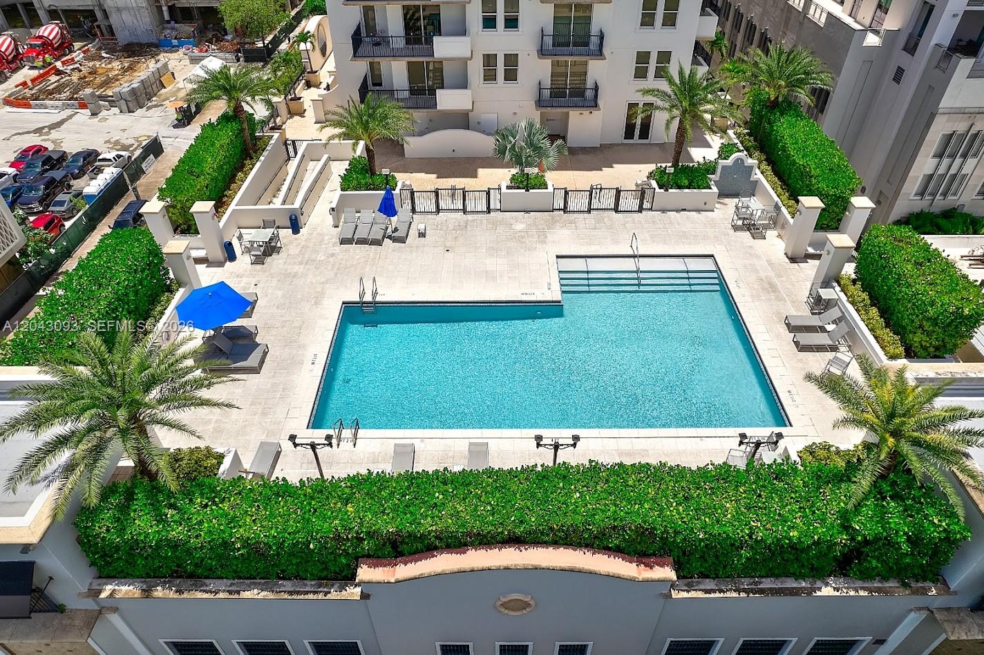 An aerial view shows a rectangular swimming pool surrounded by a patio, landscaping, and lounge chairs — 4100 Salzedo St # 502, Coral Gables FL 33146, CORAL GABLES, FL