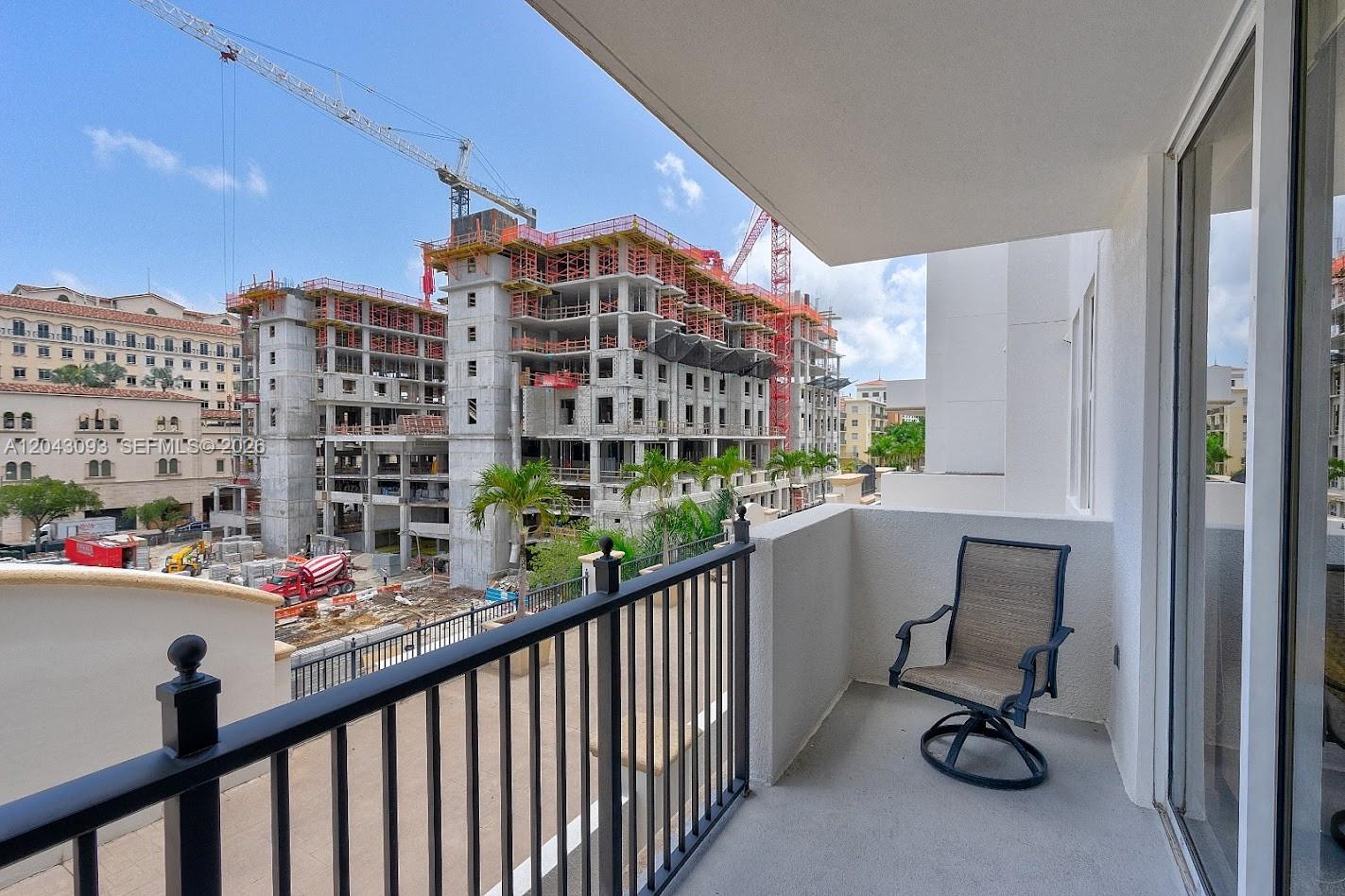 A balcony with a single chair overlooks a large construction site with cranes — 4100 Salzedo St # 502, Coral Gables FL 33146, CORAL GABLES, FL