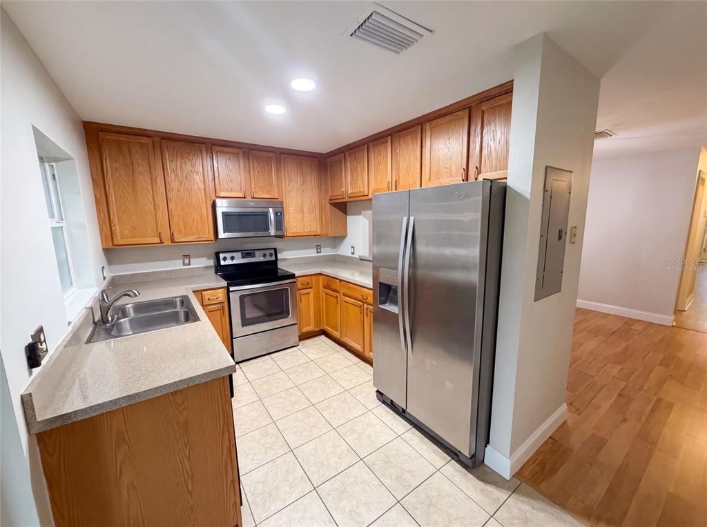 A kitchen features oak cabinets, stainless steel appliances, tile flooring, and light-colored countertops — 112 COQUINA BAY DRIVE, ST PETERSBURG, FL