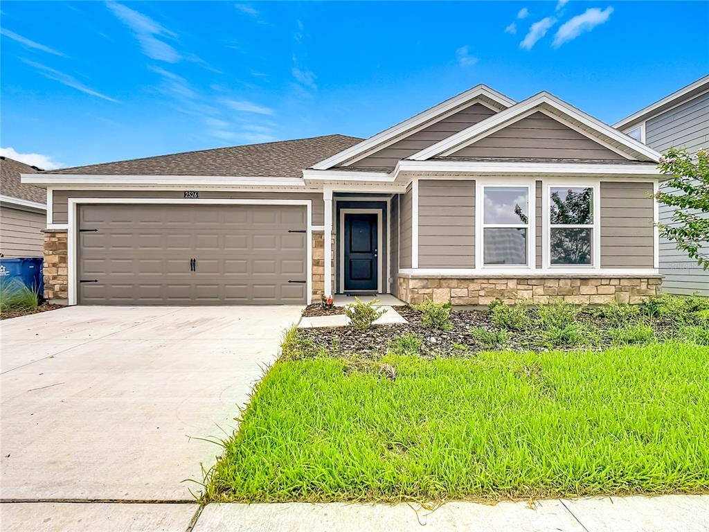 A single-story house with a brown garage, stone accents, and a front lawn — 2526 AVEENO AVENUE, HAINES CITY, FL