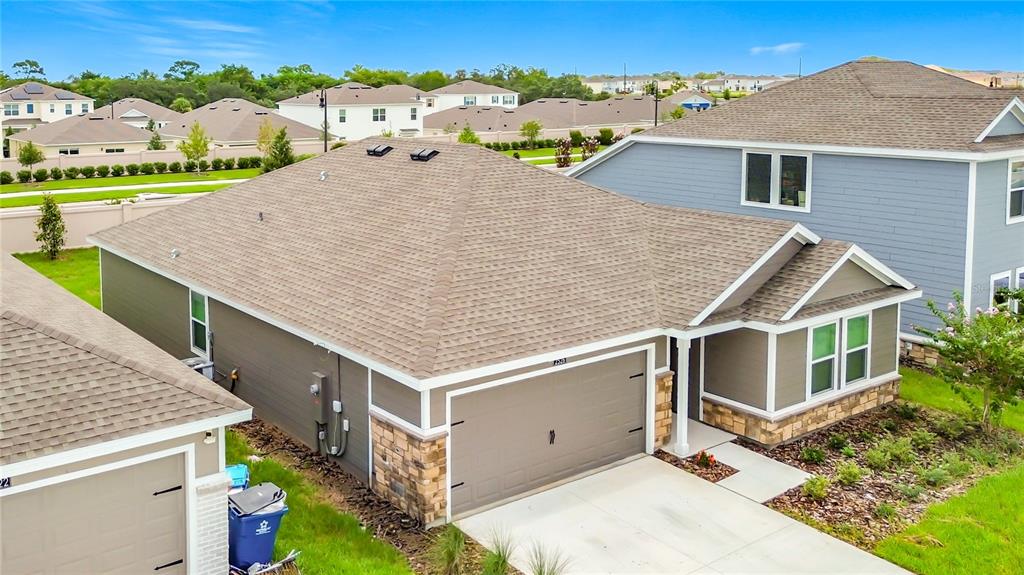 An aerial view shows a single-story suburban house with a tan exterior and stone accents — 2526 AVEENO AVENUE, HAINES CITY, FL