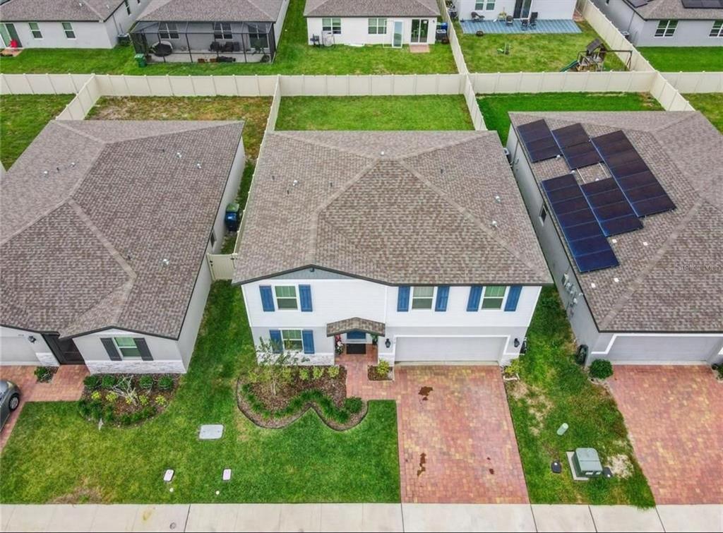An aerial view shows a two-story house with a brick driveway and solar panels — 1210 ZAMBRANA COURT, WINTER HAVEN, FL