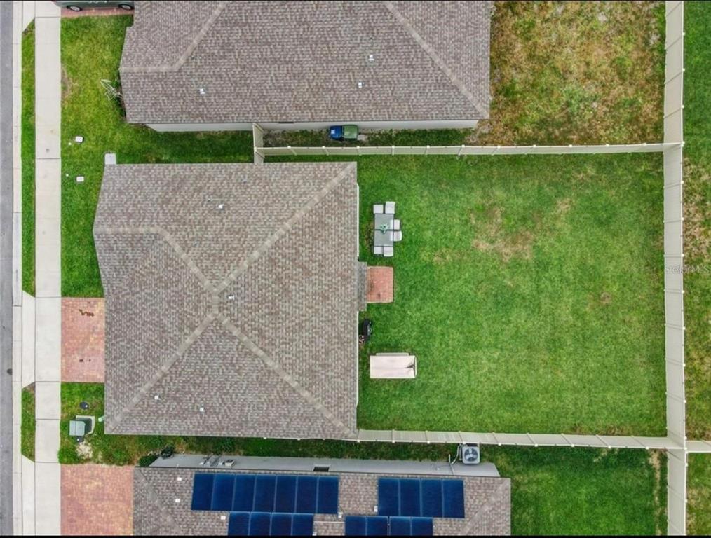 An aerial view shows a house with a fenced backyard, patio furniture, and solar panels — 1210 ZAMBRANA COURT, WINTER HAVEN, FL