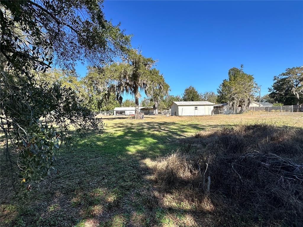 A grassy lot features several outbuildings, mature trees with Spanish moss, and a wire fence — 750 N WEKIWA SPRINGS ROAD, APOPKA, FL