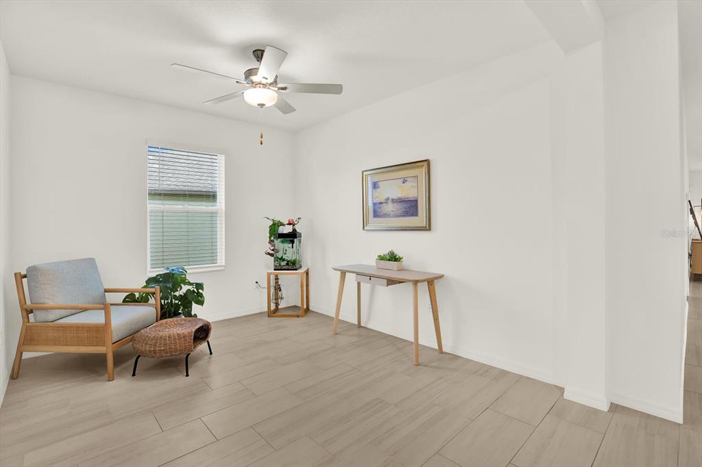 A bright room features light wood-look tile flooring, a ceiling fan, and minimalist furniture — 11307 LINDEN DEPOT ROAD, SAN ANTONIO, FL