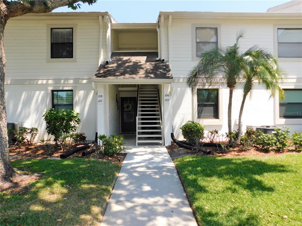 A two-story apartment building exterior with a central staircase and numbered unit signs — 107 WINDWARD PLACE UNIT 107, OLDSMAR, FL