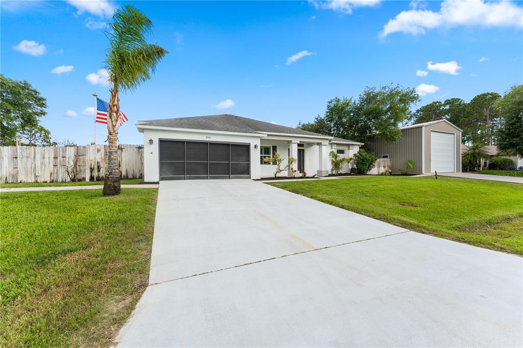 A single-story house with a screened garage, a concrete driveway, and a detached metal workshop — 2943 TOULON ROAD SE, PALM BAY, FL