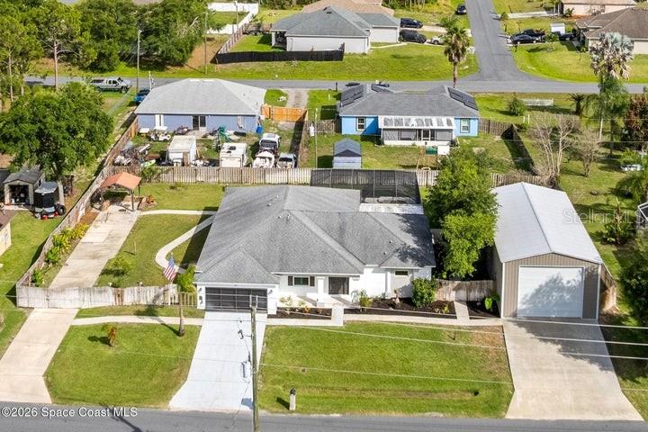 An aerial view shows a residential house with a detached garage and a fenced yard — 2943 TOULON ROAD SE, PALM BAY, FL