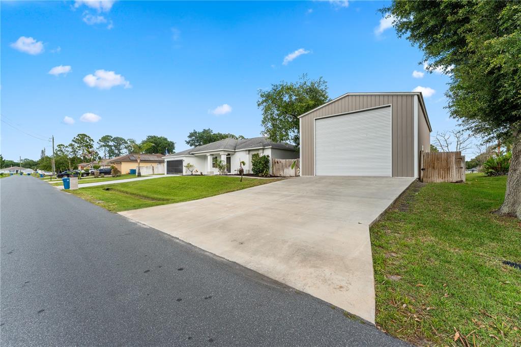 A detached metal garage sits on a concrete driveway next to a single-story house — 2943 TOULON ROAD SE, PALM BAY, FL