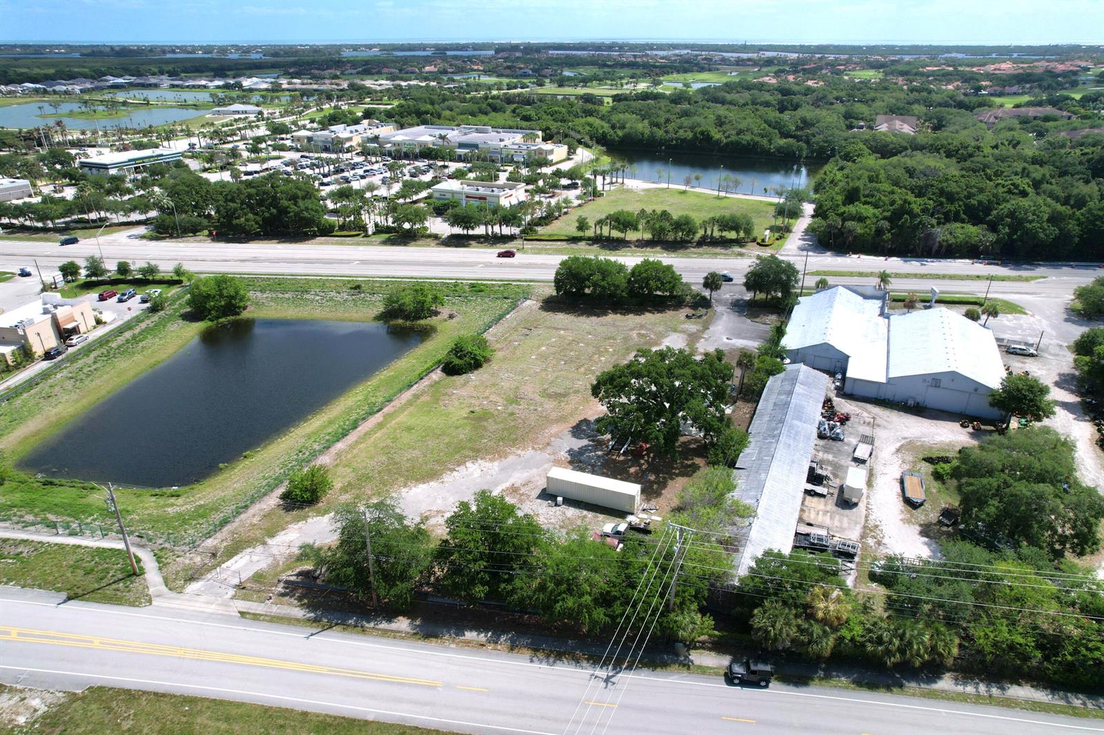 An aerial view shows a commercial property with a warehouse, vacant land, and a pond — 5145 Us Highway 1 Highway, Vero Beach FL 32967, VERO BEACH, FL