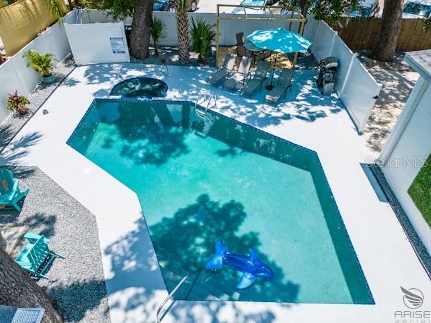 An aerial view shows a swimming pool with a blue inflatable toy in a fenced backyard — 301 LIVE OAK STREET, NEW SMYRNA BEACH, FL