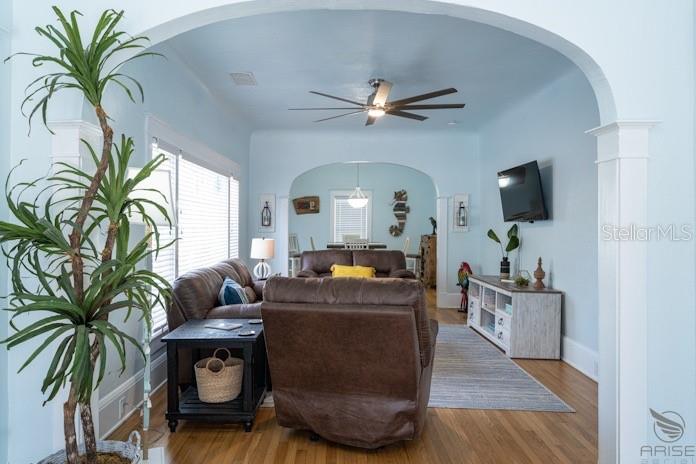 A living room with light blue walls, hardwood floors, and an arched entryway leading to a dining area — 301 LIVE OAK STREET, NEW SMYRNA BEACH, FL