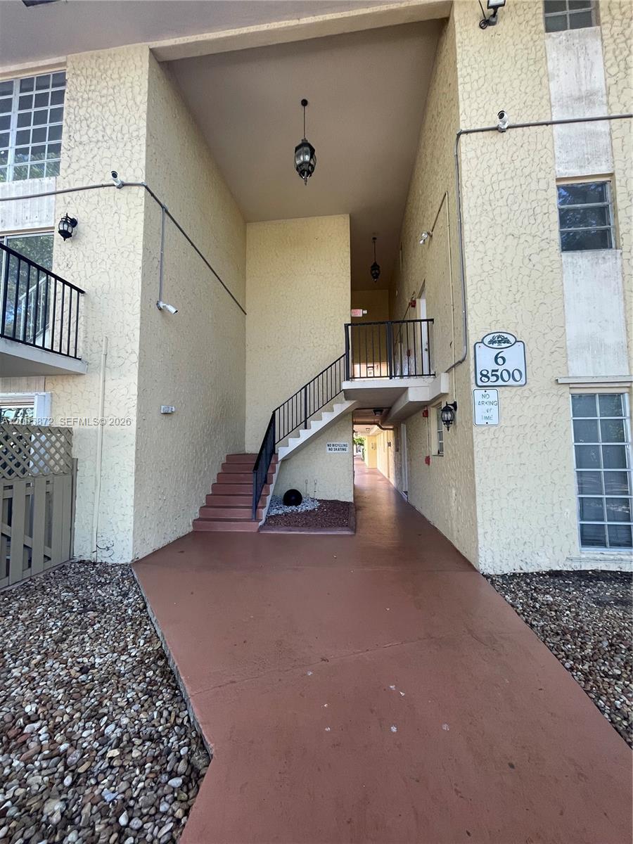 An exterior view of a multi-story apartment building entrance with stairs leading to a balcony — 8500 SW 109th Ave # 229, Miami FL 33173, MIAMI, FL
