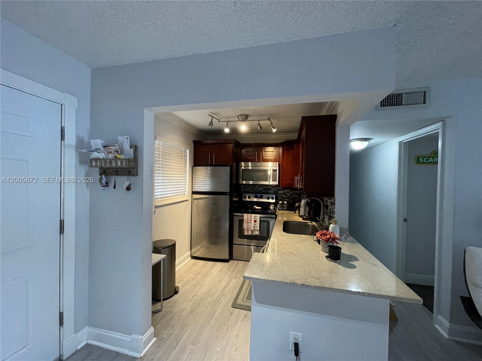 A kitchen features stainless steel appliances, dark wood cabinets, and a light-colored granite countertop — 8500 SW 109th Ave # 229, Miami FL 33173, MIAMI, FL