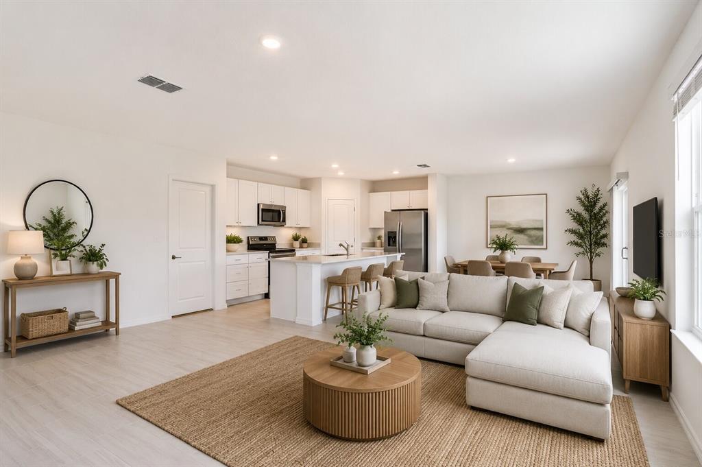 An open-concept living room and kitchen featuring white cabinetry, a kitchen island, and neutral furniture — 17534 SHIREWOOD WAY, LAND O LAKES, FL
