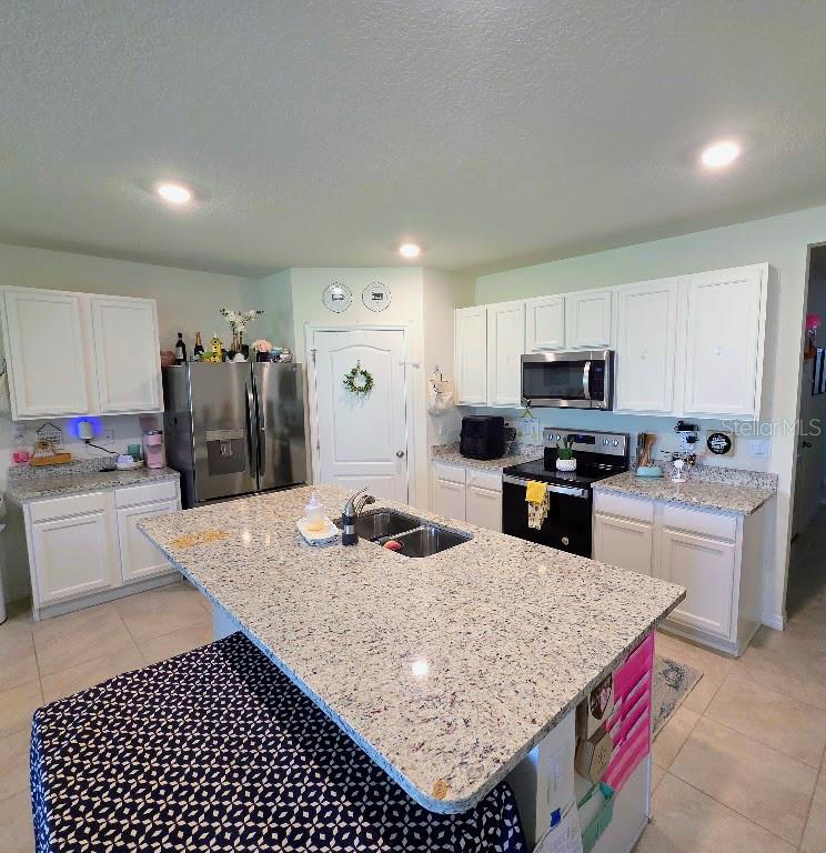 A kitchen features white cabinets, granite countertops, a central island, and stainless steel appliances — 5268 GREENHEART AVENUE, MOUNT DORA, FL