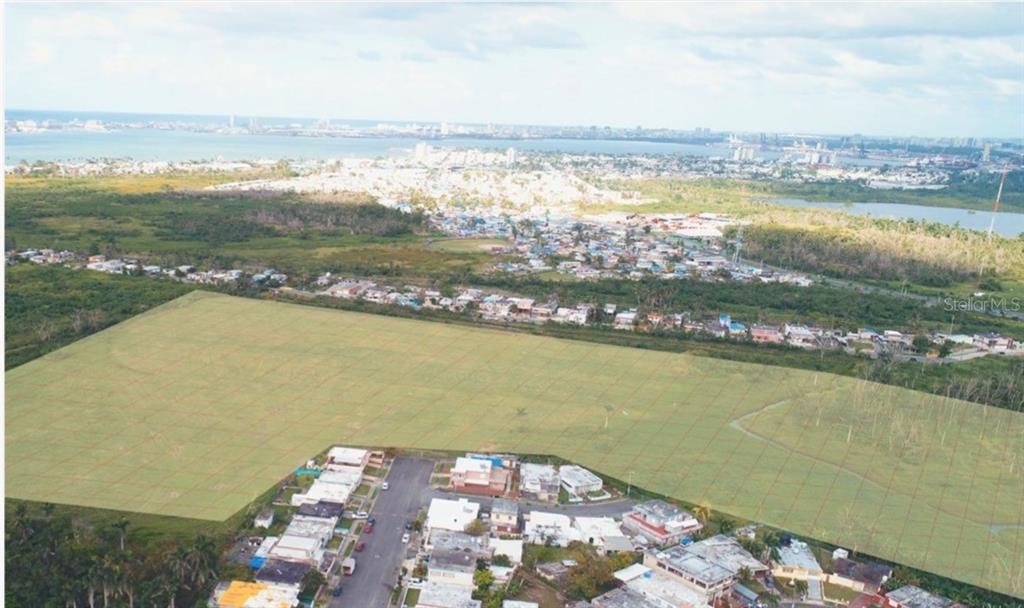 An aerial view shows a large, vacant rectangular plot of land adjacent to a residential neighborhood — 28 ACRES VACANT RESIDENTIAL LAND – CATAÑO, PUERTO, CATANO, PR