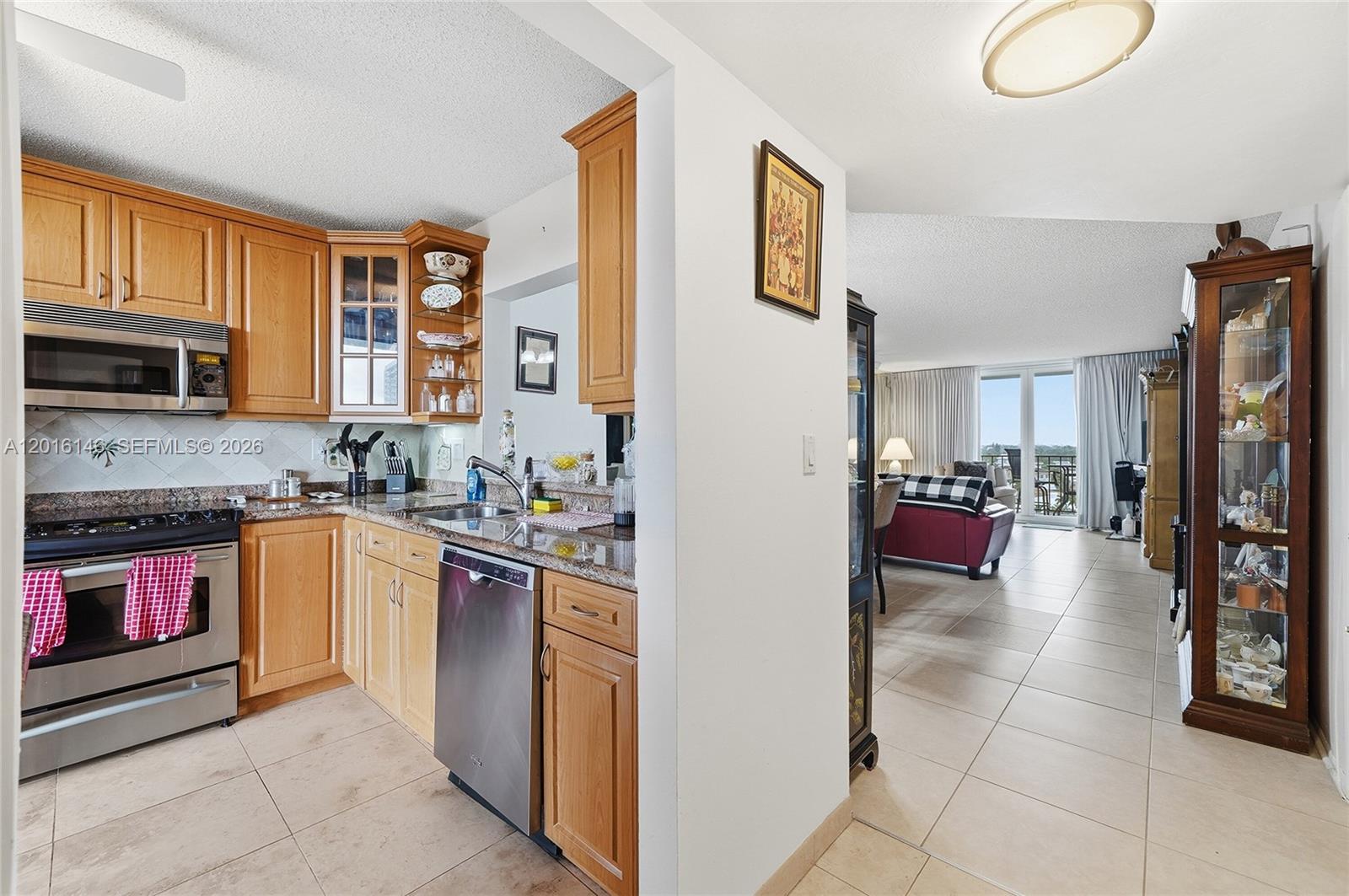 A kitchen with light wood cabinets and stainless steel appliances opens into a living area — 521 N Riverside Dr # 606, Pompano Beach FL 33062, POMPANO BEACH, FL