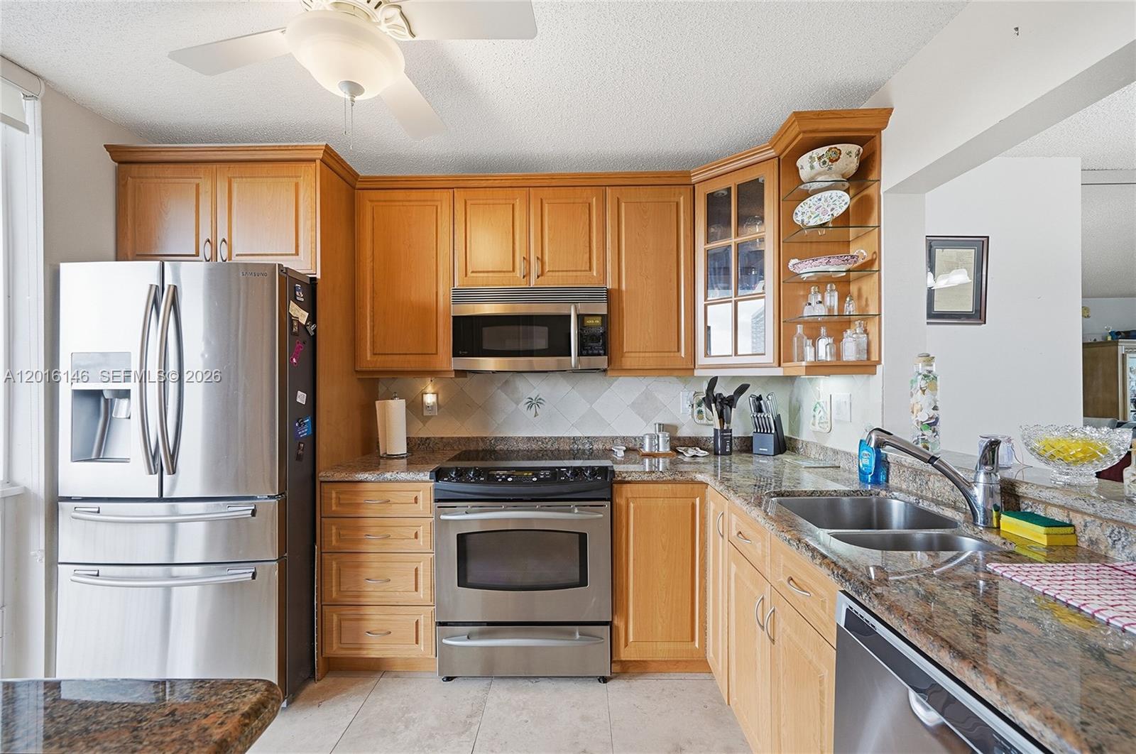 A kitchen features light wood cabinets, stainless steel appliances, and granite countertops — 521 N Riverside Dr # 606, Pompano Beach FL 33062, POMPANO BEACH, FL