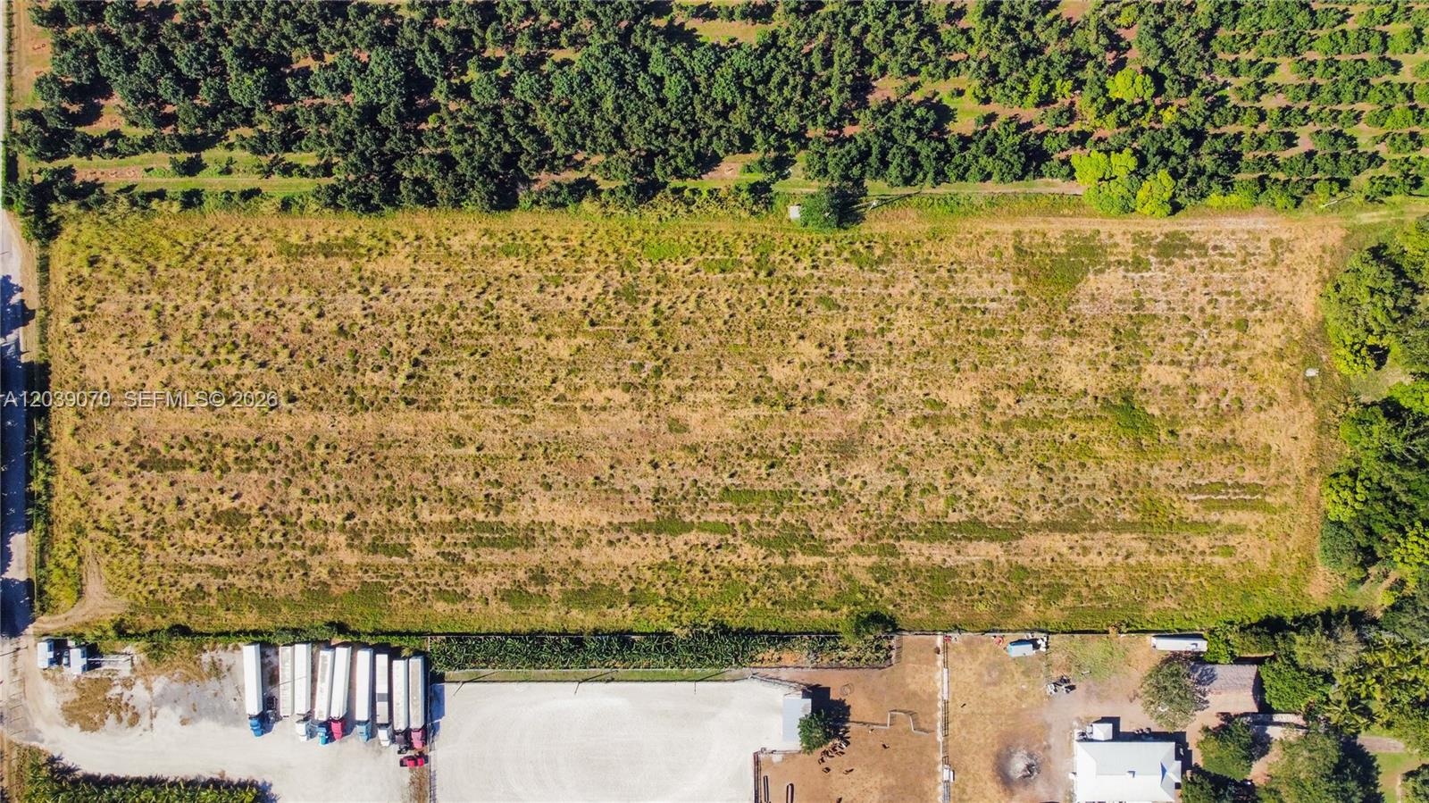An aerial view shows a large rectangular grassy lot bordered by trees and buildings — 14350 SW 232nd St, Miami FL 33170, MIAMI, FL