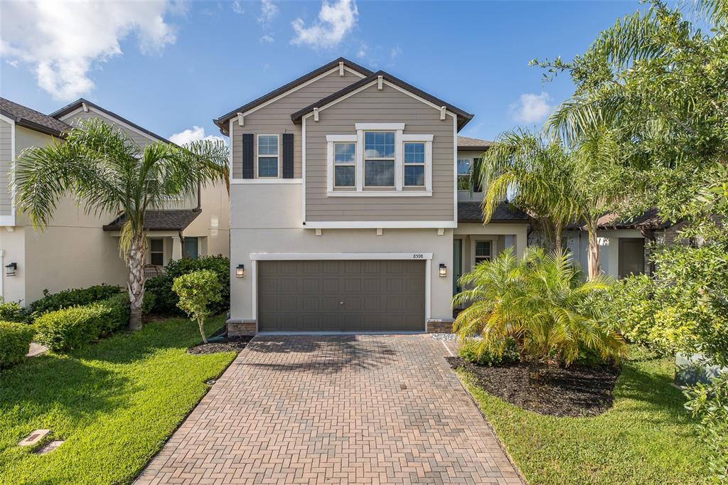 A two-story suburban house with a paved driveway, a garage, and palm trees in front — 8598 CAMPUS WOODS WAY, NEW PORT RICHEY, FL