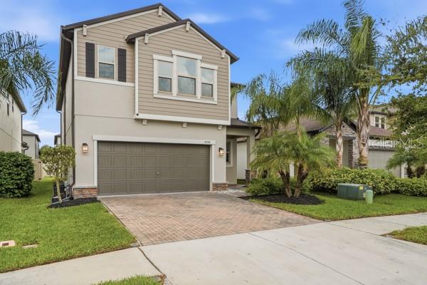 A two-story house with a beige exterior, a two-car garage, and palm trees in front — 8598 CAMPUS WOODS WAY, NEW PORT RICHEY, FL