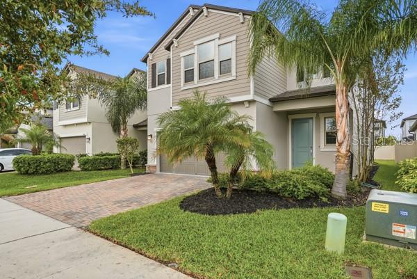 A two-story suburban house with a paved driveway, palm trees, and a light-colored exterior — 8598 CAMPUS WOODS WAY, NEW PORT RICHEY, FL