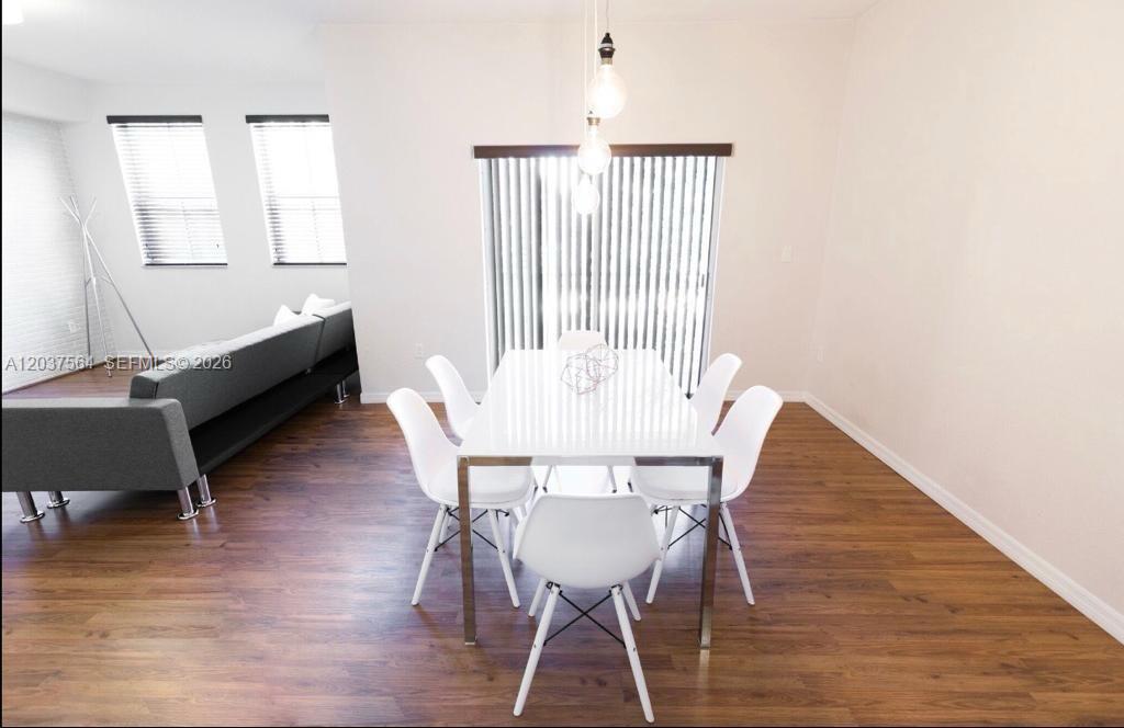 A dining area with a white table and chairs sits on wood-look flooring — 10805 NW 89th Ter # 4, Doral FL 33178, DORAL, FL