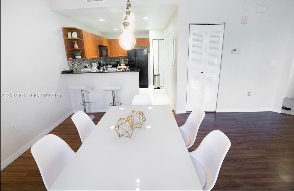 A dining area with a white table and chairs sits in front of a kitchen — 10805 NW 89th Ter # 4, Doral FL 33178, DORAL, FL
