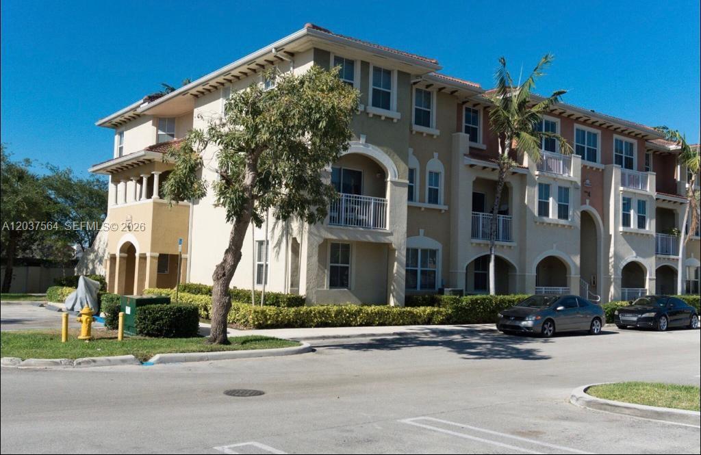 A multi-story apartment building with stucco walls, arched balconies, and a parking lot in front — 10805 NW 89th Ter # 4, Doral FL 33178, DORAL, FL