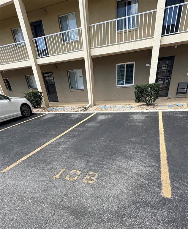 The exterior of a multi-story apartment building features parking spaces and a white car — 3514 LAKE BAYSHORE DRIVE UNIT K-108, BRADENTON, FL
