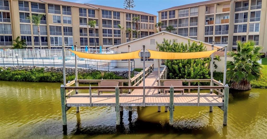 A wooden dock with benches and a yellow shade sail sits on a pond — 3514 LAKE BAYSHORE DRIVE UNIT K-108, BRADENTON, FL