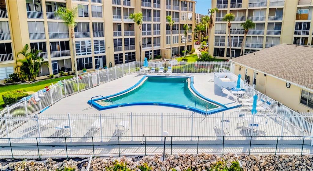 An outdoor swimming pool is enclosed by a white fence in front of apartment buildings — 3514 LAKE BAYSHORE DRIVE UNIT K-108, BRADENTON, FL