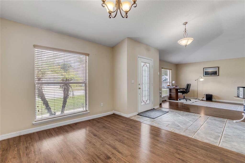 A dining area with wood flooring transitions to a tiled entryway and a home office — 1510 BRAYTON CIRCLE, DELTONA, FL