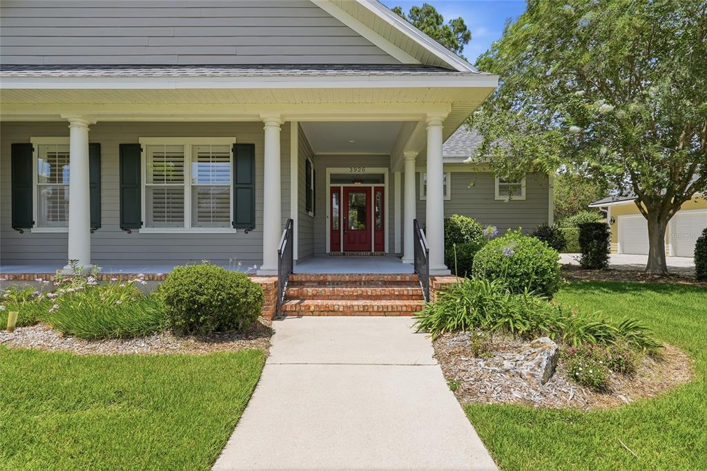 A concrete walkway leads to the covered front porch of a gray house with columns — 3926 SW 69TH AVENUE, GAINESVILLE, FL