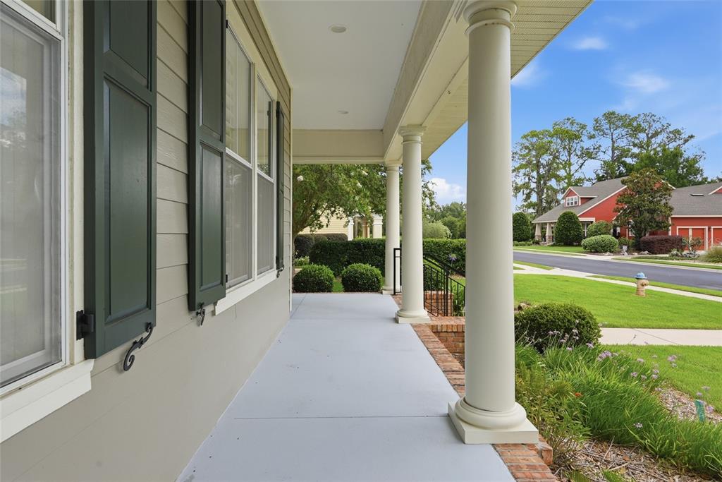 A covered front porch features light gray flooring, white columns, and dark green window shutters — 3926 SW 69TH AVENUE, GAINESVILLE, FL