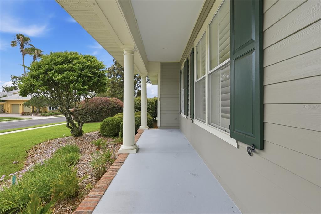 A covered front porch with white columns, gray flooring, and green shutters on the house — 3926 SW 69TH AVENUE, GAINESVILLE, FL